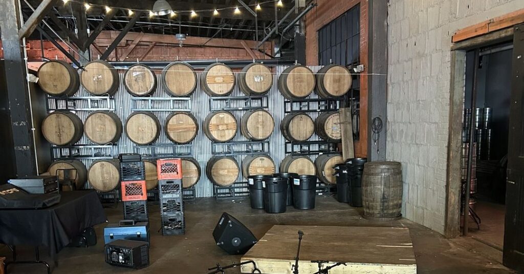 A small stage and some sound equipment in front of a wall of barrel casks.
